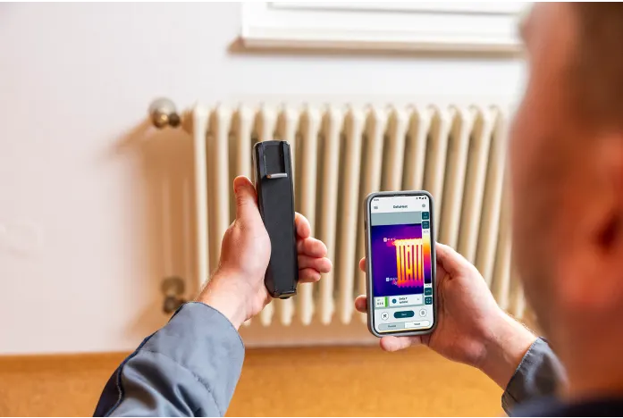 Person using a smartphone with thermal imaging app to check a radiator