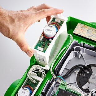 Close-up of a hand interacting with electronic components inside a green device.