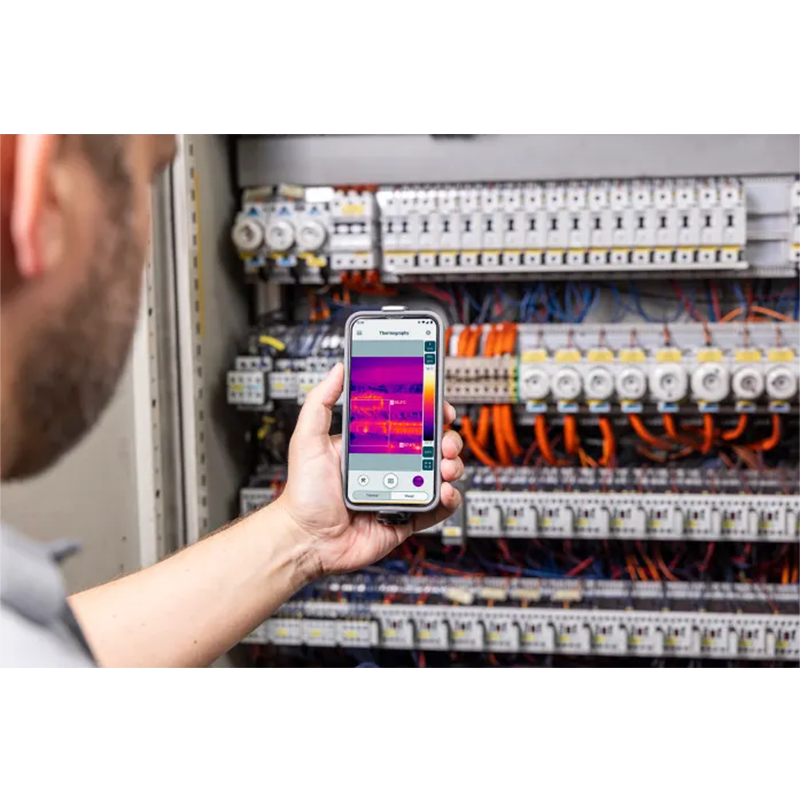 Person using a smartphone with thermal imaging app on electrical panel