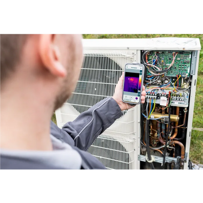Person using a thermal imaging phone to inspect an air conditioning unit.